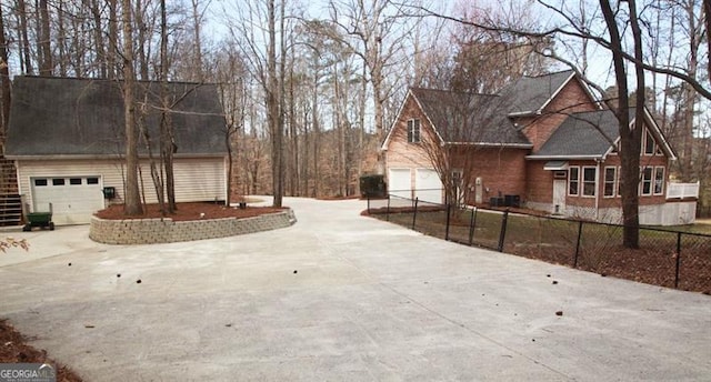 exterior space with a garage, concrete driveway, and fence