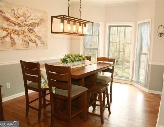 dining area with baseboards, wood finished floors, and crown molding