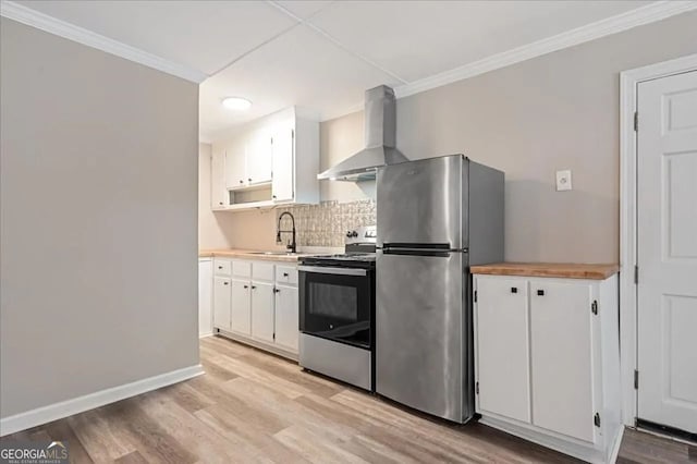 kitchen with light wood-style floors, ornamental molding, stainless steel appliances, wall chimney range hood, and a sink