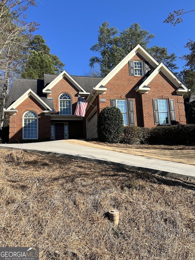 traditional home featuring driveway and brick siding