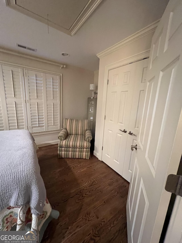 bedroom with a closet, wood finished floors, visible vents, and attic access