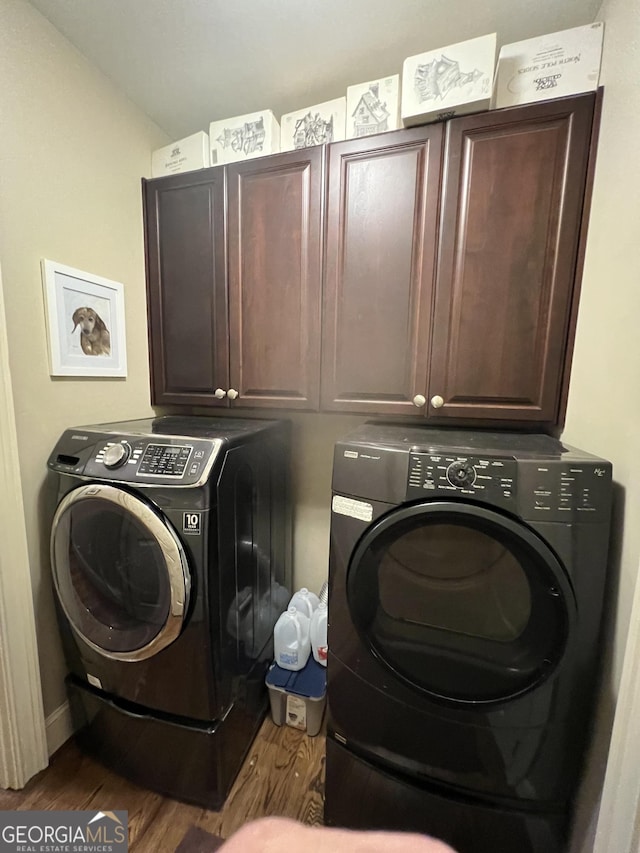 clothes washing area with dark wood-style floors, separate washer and dryer, and cabinet space