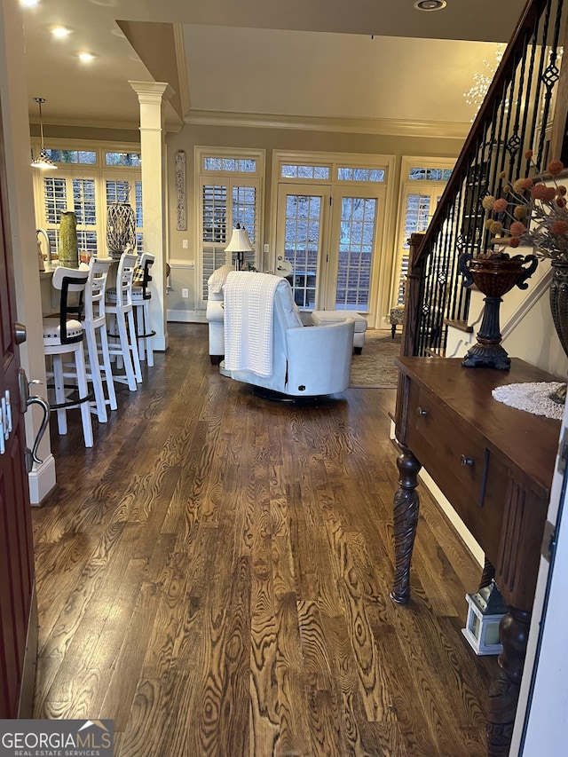 living room featuring dark wood-style floors, ornamental molding, stairway, and ornate columns