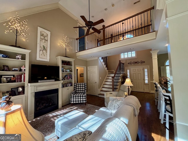 living area with ornate columns, a high ceiling, stairway, and wood finished floors