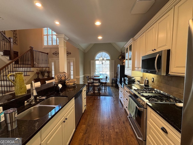 kitchen with appliances with stainless steel finishes, dark wood-type flooring, vaulted ceiling, ornate columns, and a sink