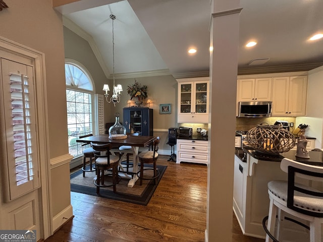 dining space featuring dark wood-type flooring, vaulted ceiling, crown molding, a chandelier, and recessed lighting