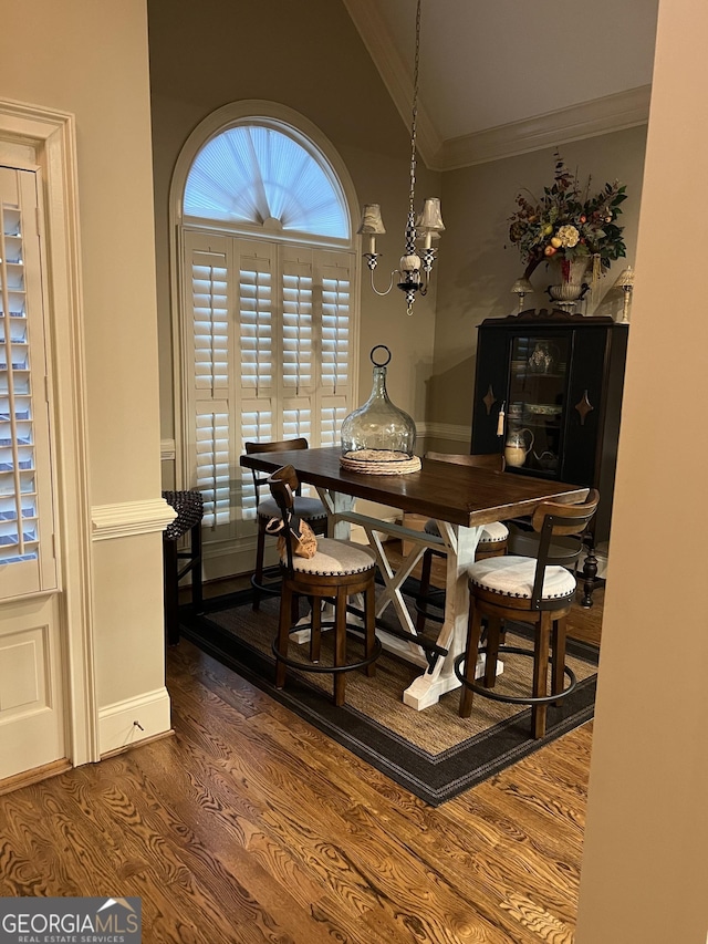 dining room with ornamental molding, vaulted ceiling, dark wood finished floors, and baseboards