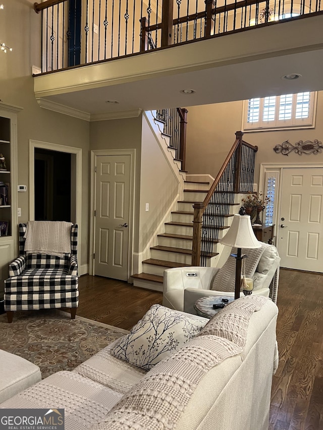 living room with stairs, a towering ceiling, and wood finished floors