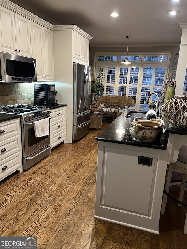 kitchen featuring stainless steel appliances, dark wood-type flooring, a sink, white cabinetry, and ornamental molding