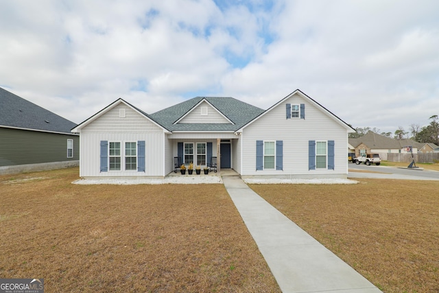 view of front of home featuring a shingled roof, a porch, a front lawn, and board and batten siding