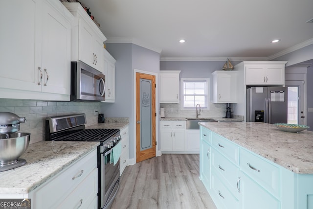 kitchen featuring stainless steel appliances, ornamental molding, a sink, and white cabinetry