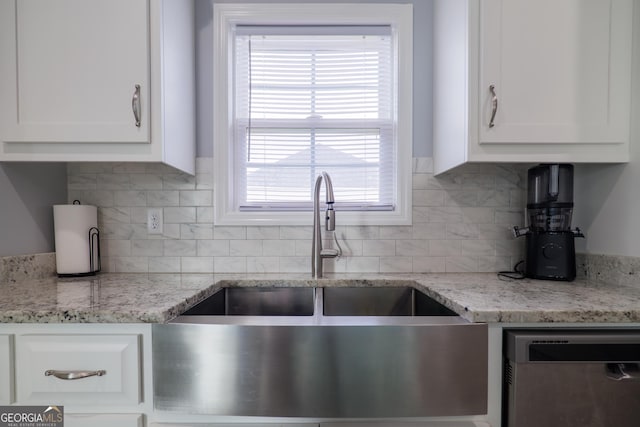 kitchen with tasteful backsplash, white cabinets, a sink, and stainless steel dishwasher