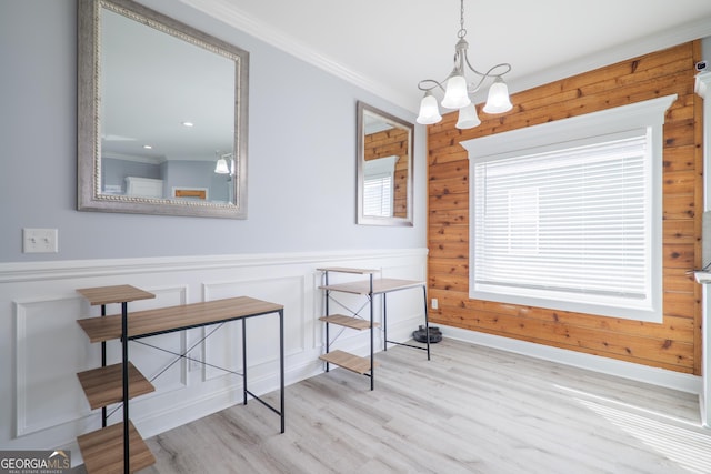 dining area with ornamental molding, wainscoting, wood finished floors, and an inviting chandelier