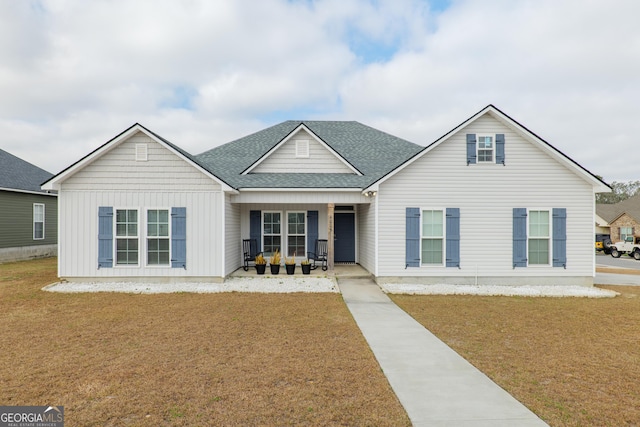 view of front of home with a shingled roof, a front lawn, and a porch