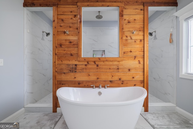 bathroom featuring marble finish floor, a marble finish shower, baseboards, and a freestanding tub