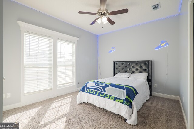 carpeted bedroom featuring a ceiling fan, visible vents, and baseboards