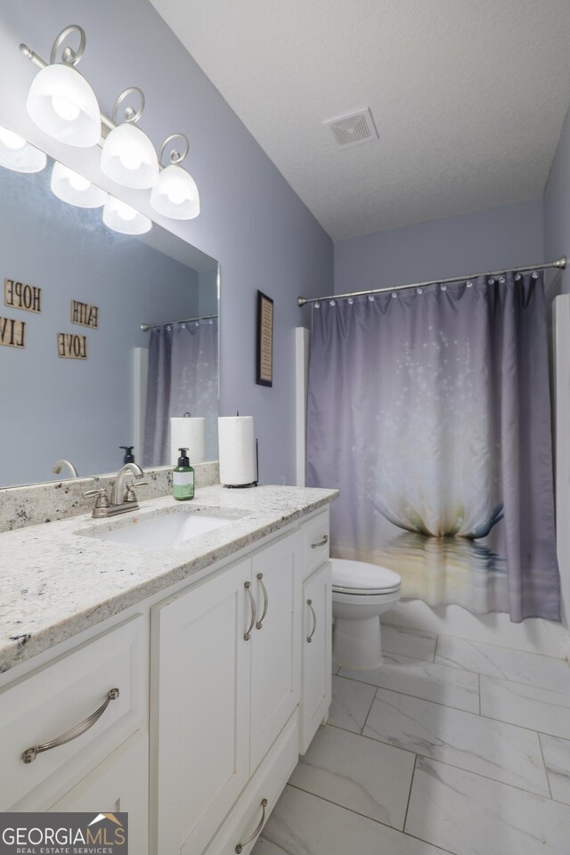 bathroom with a textured ceiling, toilet, vanity, visible vents, and marble finish floor