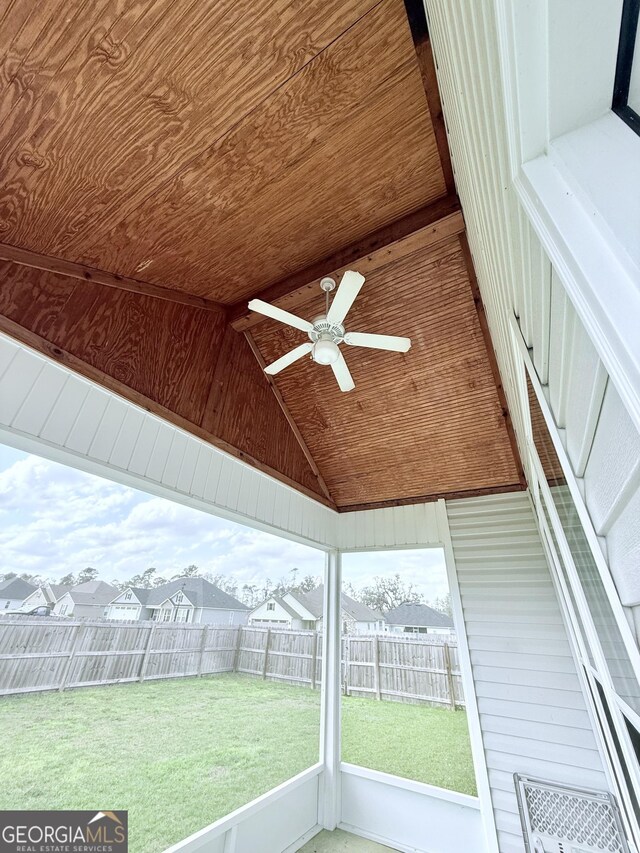 rear view of property featuring a fenced backyard, a sunroom, a yard, roof with shingles, and roof mounted solar panels