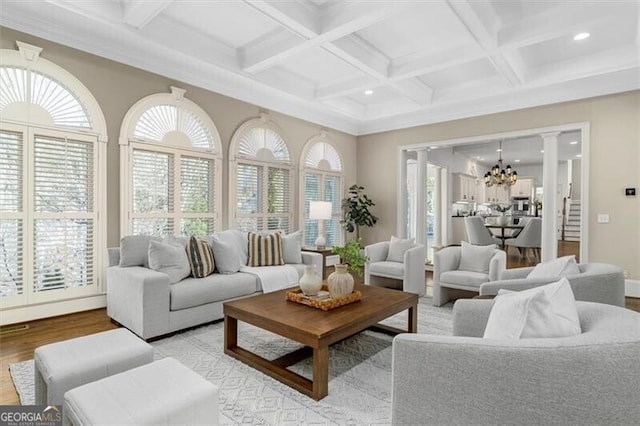 sunroom / solarium featuring an inviting chandelier, decorative columns, coffered ceiling, and beam ceiling