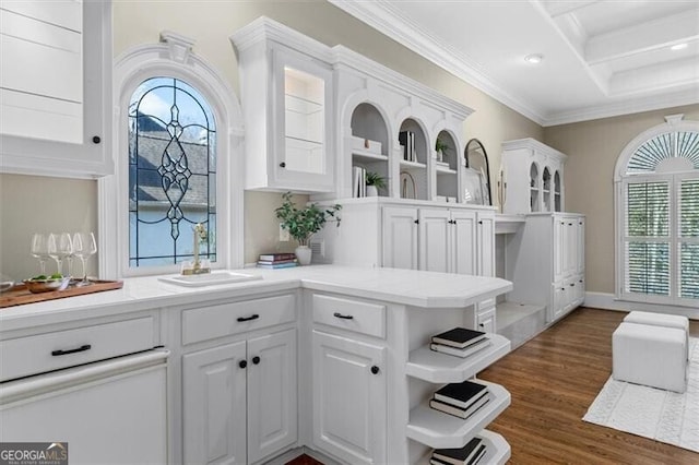 kitchen featuring a peninsula, a sink, white cabinetry, and crown molding