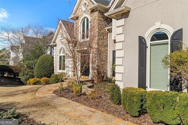 doorway to property with stone siding and stucco siding