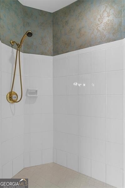 full bathroom featuring tiled shower and wallpapered walls