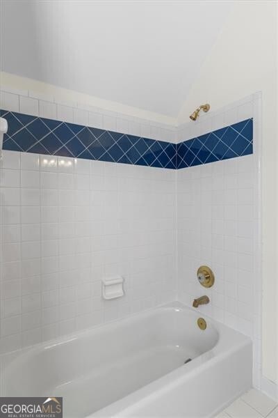 bathroom featuring lofted ceiling, shower / bath combination, and tile patterned floors