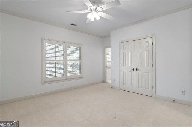 unfurnished bedroom featuring carpet floors, crown molding, a closet, visible vents, and baseboards