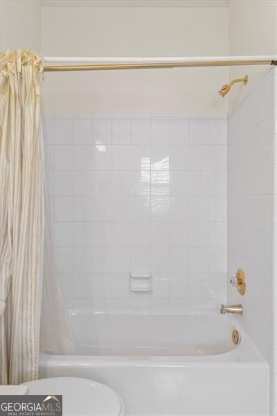 full bath with toilet and shower / tub combo with curtain