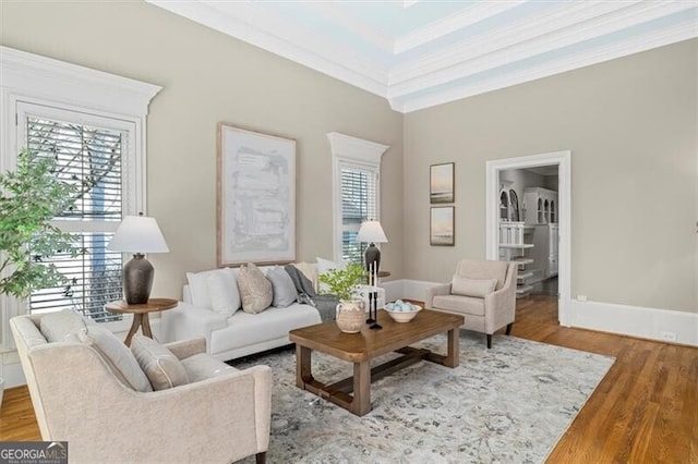 living area with ornamental molding, wood finished floors, and baseboards