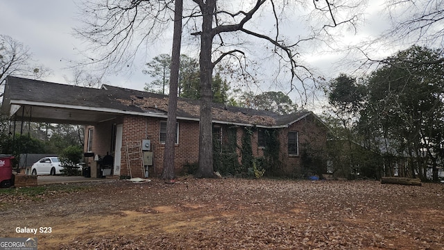 view of side of property featuring a carport and brick siding