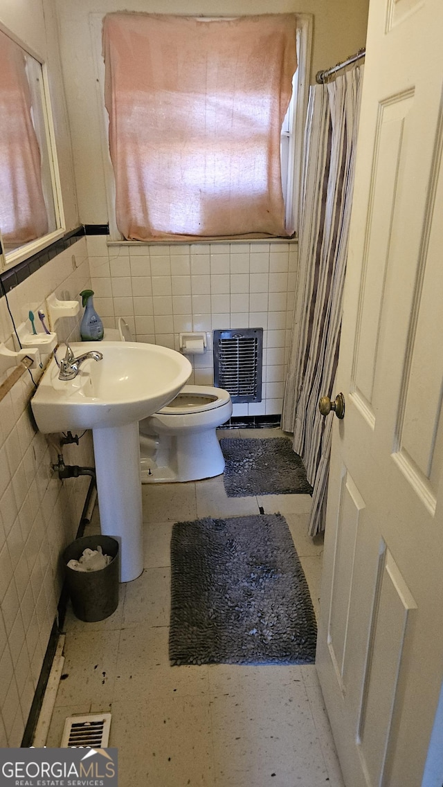 full bath featuring toilet, visible vents, and tile walls