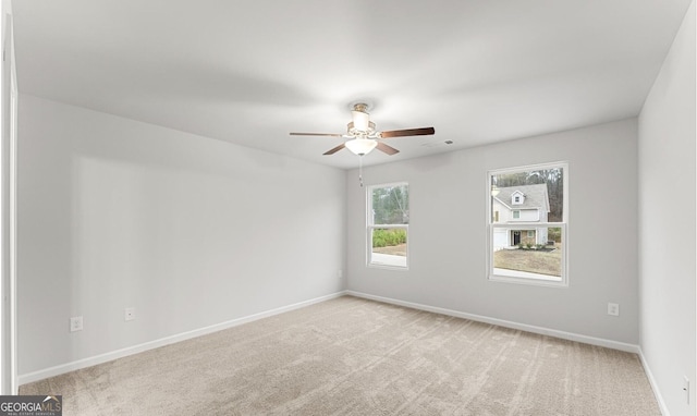 empty room with baseboards, a ceiling fan, and light colored carpet