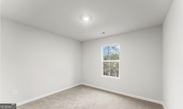 carpeted spare room featuring baseboards and visible vents