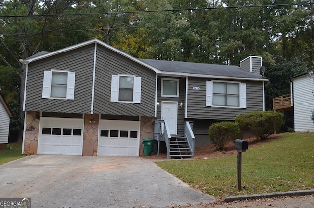 split foyer home with driveway, stone siding, an attached garage, and a front yard