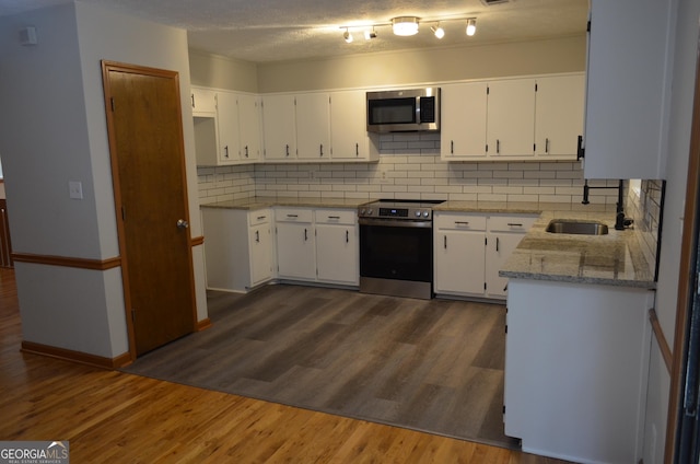 kitchen featuring light stone counters, a sink, white cabinetry, appliances with stainless steel finishes, and dark wood finished floors