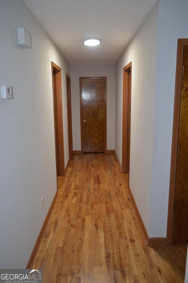 hallway with light wood finished floors and baseboards