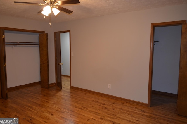 unfurnished bedroom featuring baseboards, a ceiling fan, wood finished floors, a textured ceiling, and a closet