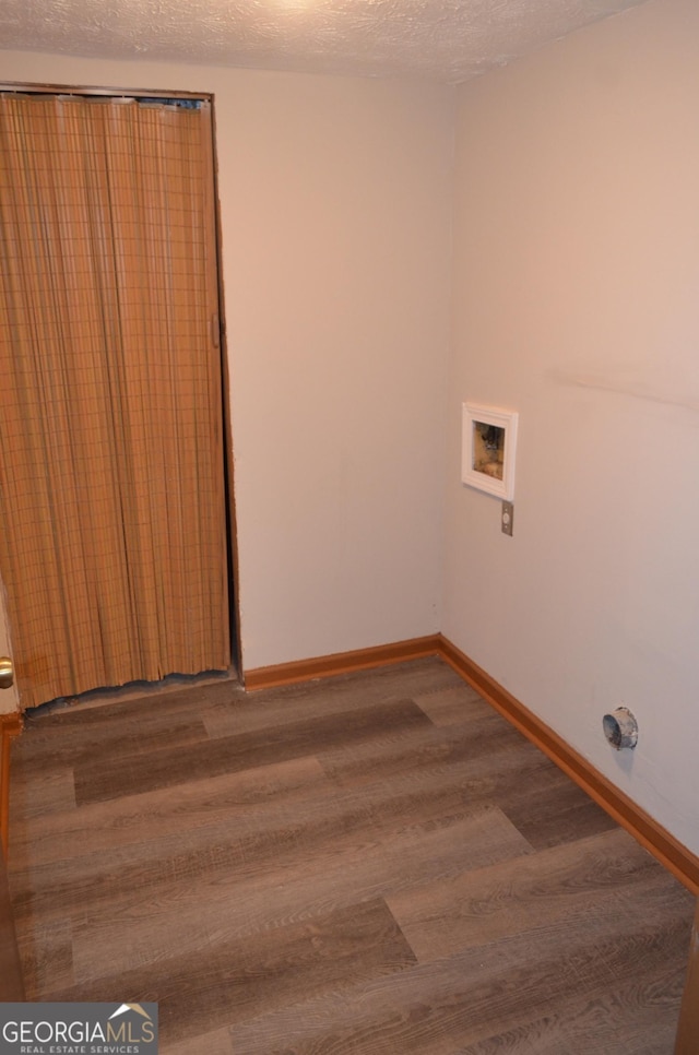 clothes washing area featuring washer hookup, a textured ceiling, wood finished floors, laundry area, and baseboards