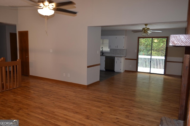 unfurnished living room with a sink, wood finished floors, a ceiling fan, and baseboards