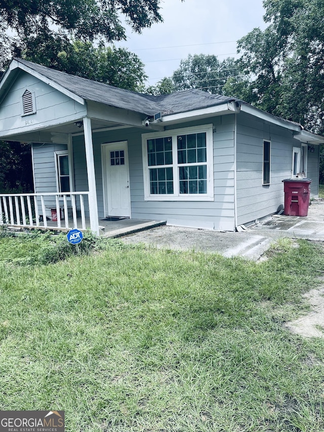 view of front of home with covered porch and a front lawn