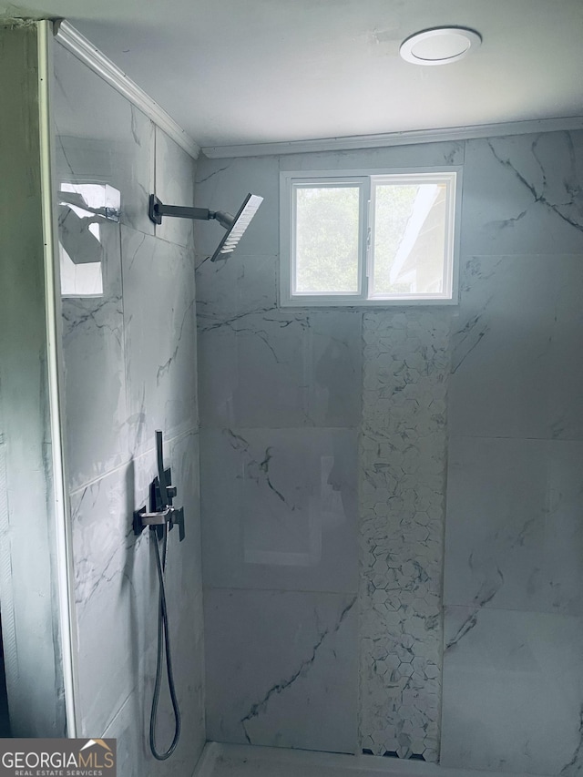 full bath with a marble finish shower and ornamental molding