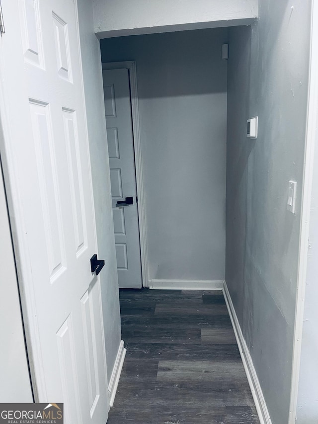 corridor featuring dark wood-style floors and baseboards