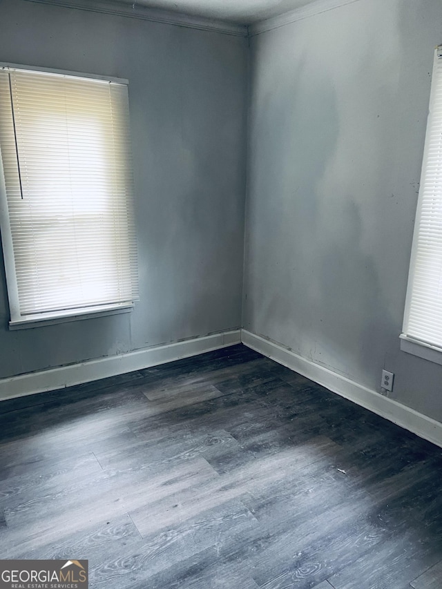 spare room featuring baseboards and wood finished floors