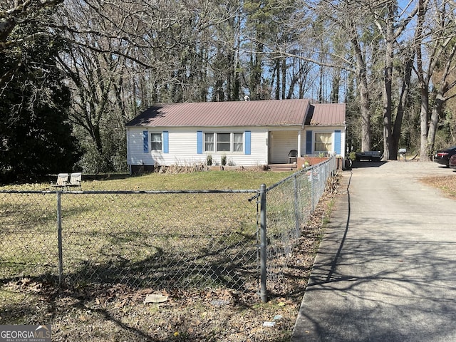 view of front facade with driveway, a fenced front yard, a front lawn, and metal roof