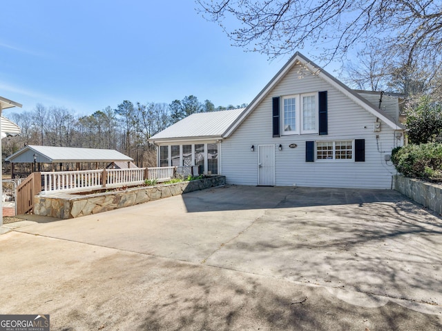 view of side of home with driveway, metal roof, and a patio