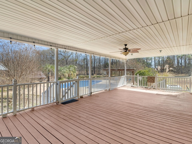 wooden deck featuring a swimming pool and a ceiling fan