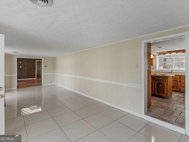 unfurnished room featuring visible vents, crown molding, a textured ceiling, and baseboards