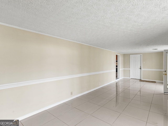 tiled empty room featuring a textured ceiling and baseboards