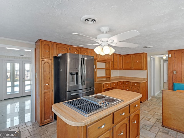 kitchen with appliances with stainless steel finishes, brown cabinets, visible vents, and stone tile floors